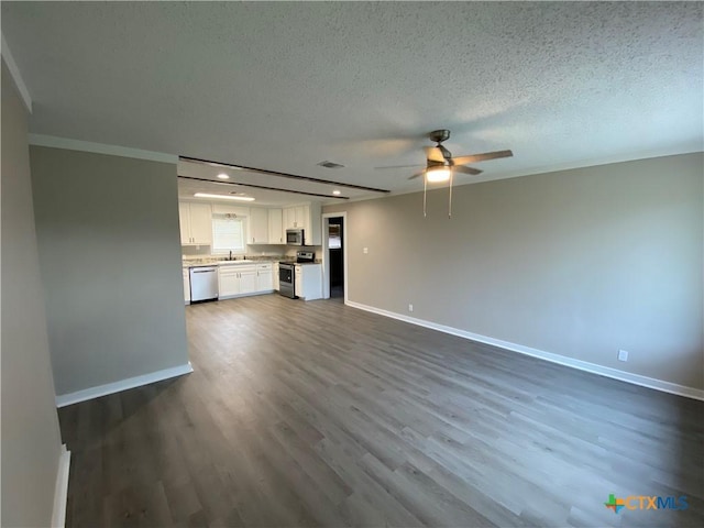 unfurnished living room with dark wood-style flooring, a sink, a textured ceiling, ceiling fan, and baseboards