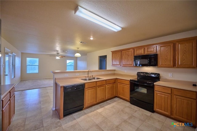 kitchen featuring black appliances, pendant lighting, kitchen peninsula, and sink