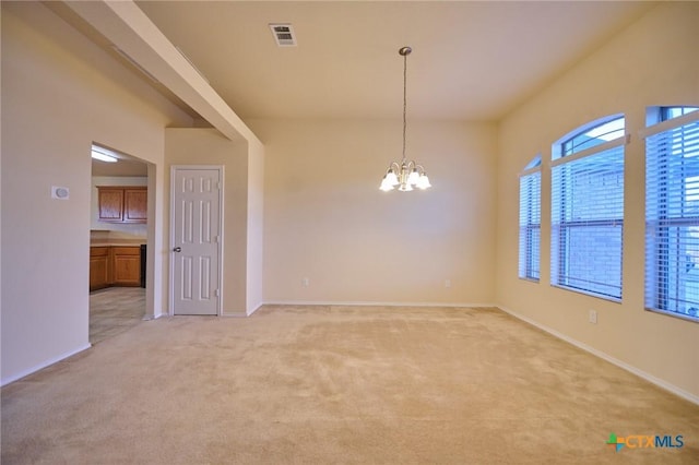 carpeted spare room featuring an inviting chandelier