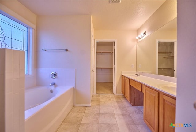 bathroom featuring a bath, vanity, a textured ceiling, and tile patterned floors