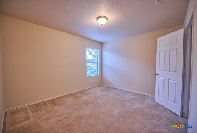 spare room featuring a textured ceiling and light colored carpet