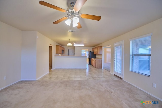 unfurnished living room featuring ceiling fan, light colored carpet, and a healthy amount of sunlight