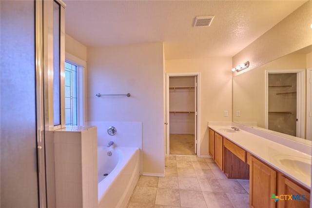 bathroom featuring a tub to relax in, tile patterned floors, vanity, and a textured ceiling