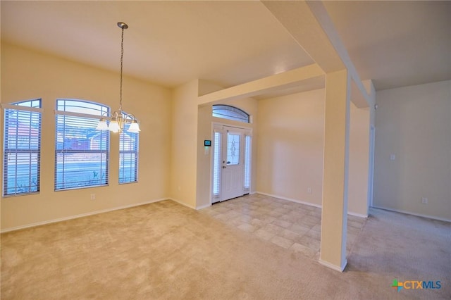 carpeted entryway featuring a wealth of natural light and a notable chandelier