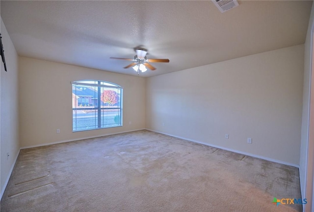 spare room with a textured ceiling, light colored carpet, and ceiling fan