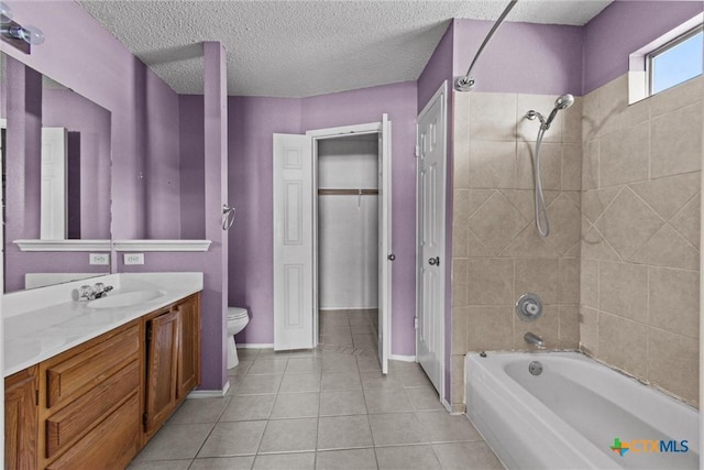 full bathroom featuring toilet, tiled shower / bath, tile patterned flooring, vanity, and a textured ceiling