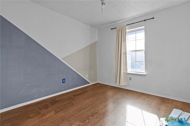 empty room featuring a textured ceiling and wood-type flooring