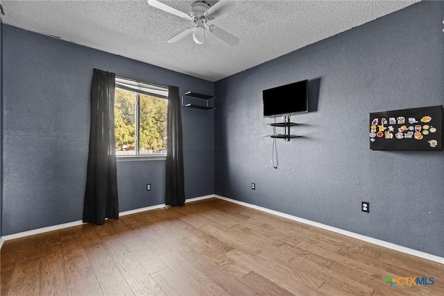 empty room with ceiling fan, a textured ceiling, and hardwood / wood-style flooring