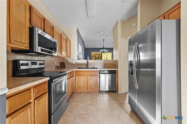 kitchen featuring pendant lighting, sink, stainless steel appliances, light tile patterned floors, and a chandelier