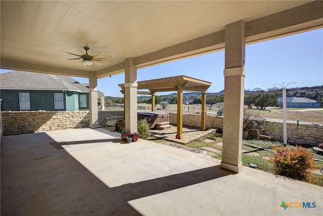 view of patio / terrace with a hot tub, ceiling fan, and a pergola