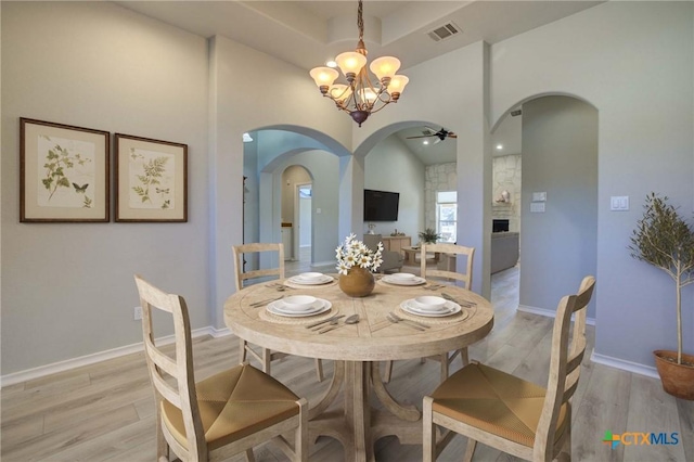 dining room with ceiling fan with notable chandelier and light hardwood / wood-style flooring