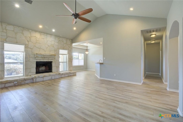 unfurnished living room featuring a stone fireplace, high vaulted ceiling, ceiling fan, and light hardwood / wood-style flooring