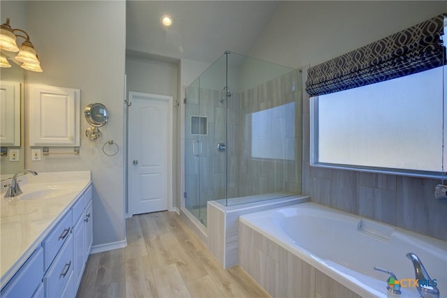 bathroom with hardwood / wood-style flooring, vanity, and plus walk in shower