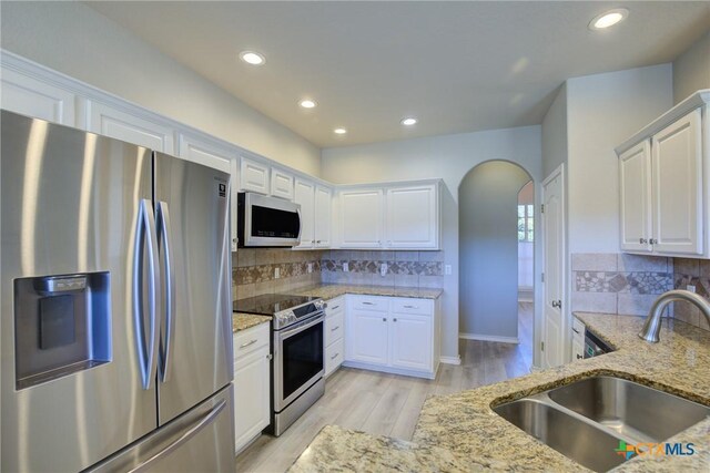 kitchen with sink, white cabinetry, tasteful backsplash, light stone counters, and stainless steel appliances