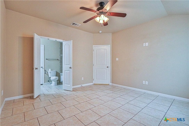 unfurnished bedroom with ceiling fan, light tile patterned floors, ensuite bathroom, and vaulted ceiling