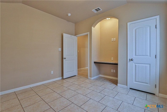 unfurnished bedroom with light tile patterned floors and vaulted ceiling