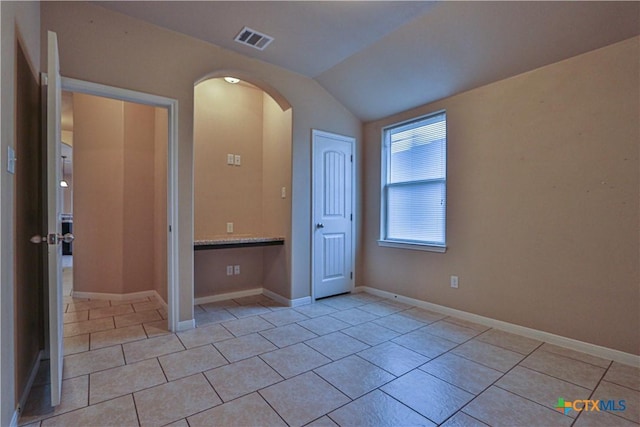 unfurnished bedroom with light tile patterned floors and vaulted ceiling