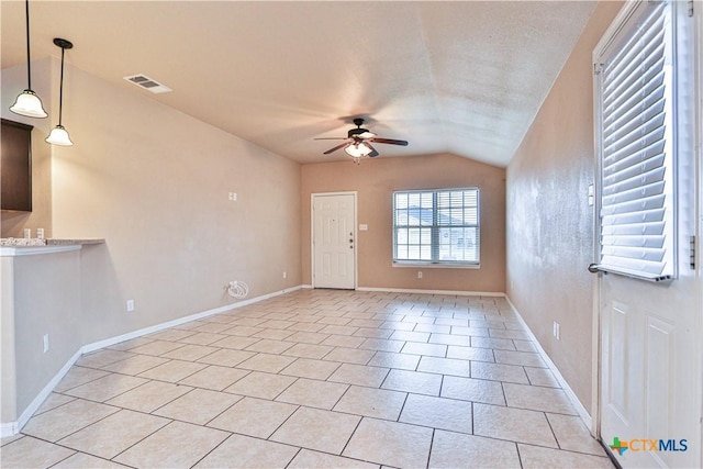 unfurnished living room with ceiling fan, light tile patterned flooring, and vaulted ceiling