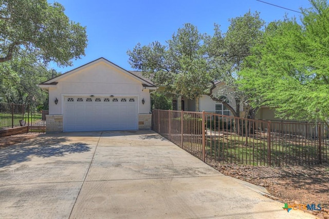 single story home featuring fence private yard, a garage, stone siding, and concrete driveway