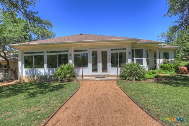 rear view of house featuring a lawn, a shingled roof, and french doors