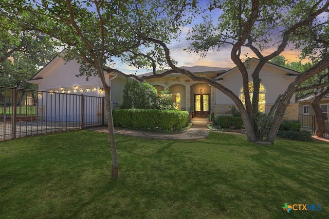 mediterranean / spanish home featuring french doors, fence, concrete driveway, and a lawn