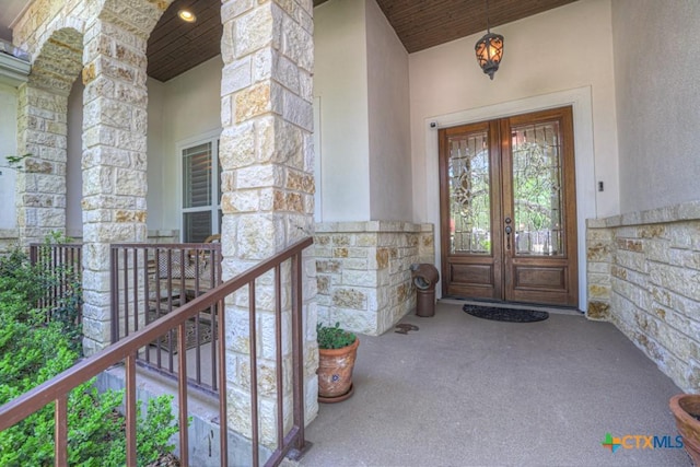 property entrance with stucco siding, french doors, and stone siding