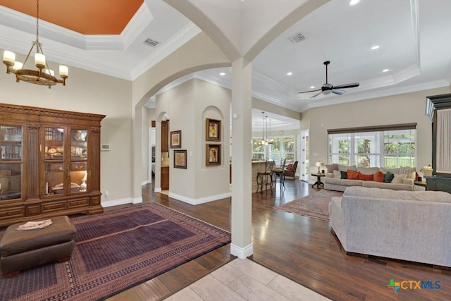 living area with visible vents, wood finished floors, a raised ceiling, arched walkways, and ceiling fan with notable chandelier
