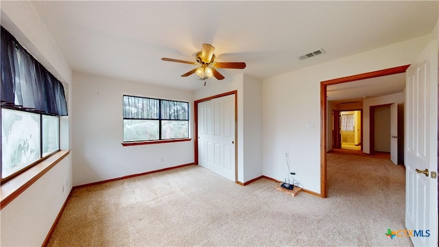 unfurnished bedroom featuring ceiling fan, light colored carpet, and a closet