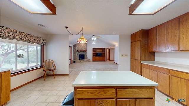 kitchen with a fireplace, a center island, vaulted ceiling, and decorative light fixtures