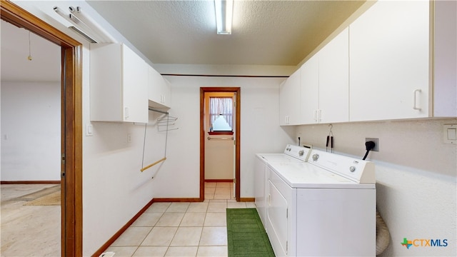 clothes washing area with cabinets, light tile patterned floors, a textured ceiling, and washing machine and clothes dryer