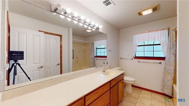 bathroom with a healthy amount of sunlight, vanity, toilet, and tile patterned flooring