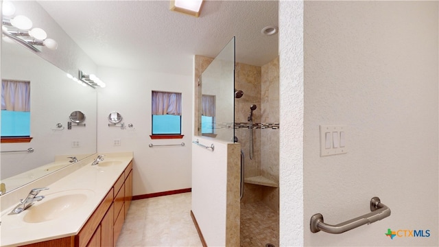 bathroom with vanity, tiled shower, and a textured ceiling