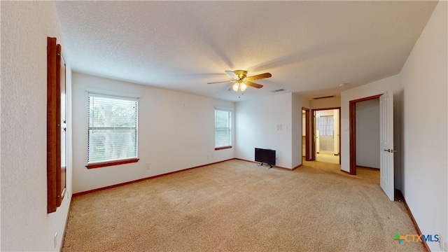 unfurnished bedroom with light carpet, multiple windows, and a textured ceiling