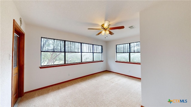 spare room featuring a healthy amount of sunlight, light colored carpet, a textured ceiling, and ceiling fan