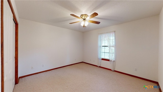 carpeted empty room with ceiling fan and a textured ceiling