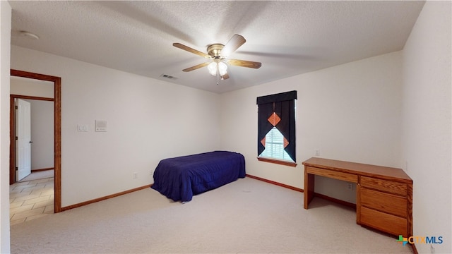 bedroom featuring ceiling fan, light colored carpet, and a textured ceiling