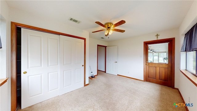 unfurnished bedroom featuring light carpet, a closet, and ceiling fan