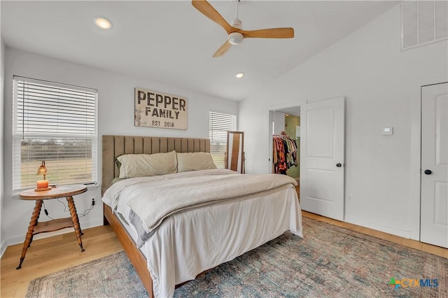 bedroom featuring ceiling fan, a spacious closet, multiple windows, and hardwood / wood-style flooring