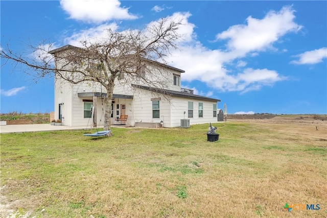 rear view of property with central AC unit and a lawn