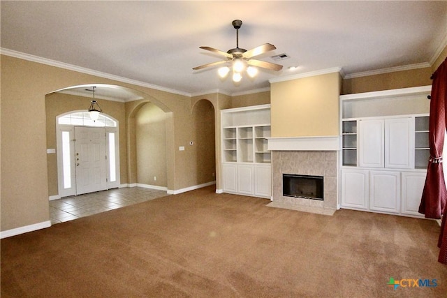 unfurnished living room featuring carpet flooring, crown molding, a fireplace, and ceiling fan