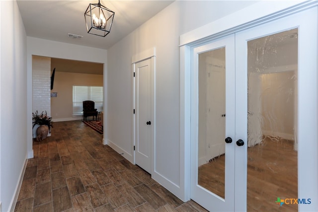 hallway with french doors, an inviting chandelier, and dark hardwood / wood-style flooring