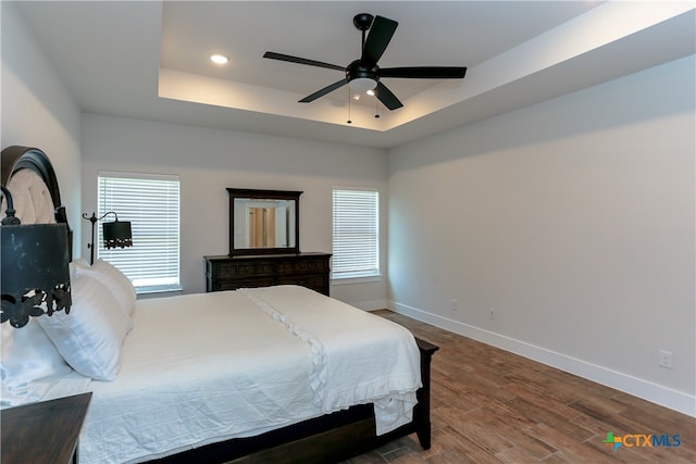 bedroom featuring hardwood / wood-style floors, ceiling fan, and a tray ceiling