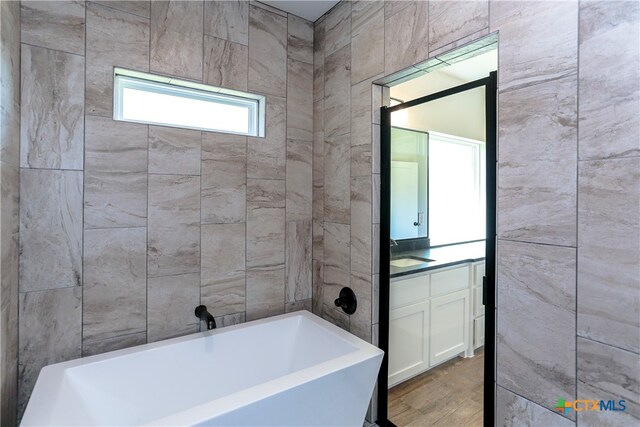 bathroom featuring a washtub, vanity, and hardwood / wood-style flooring