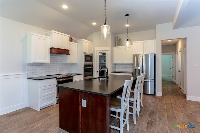 kitchen featuring stainless steel appliances, sink, a kitchen island with sink, dark hardwood / wood-style floors, and decorative light fixtures