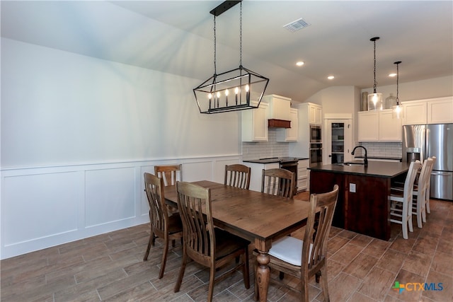 dining space featuring a chandelier, sink, and lofted ceiling