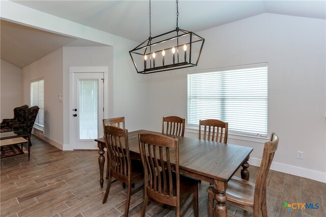 dining area featuring an inviting chandelier, wood-type flooring, and vaulted ceiling