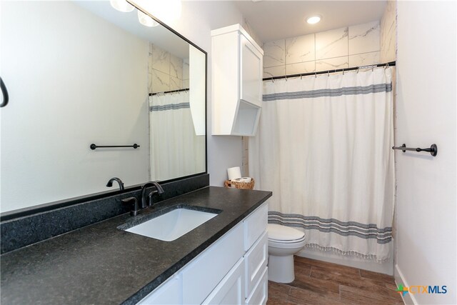 full bathroom with hardwood / wood-style floors, vanity, toilet, and shower / bath combination with curtain