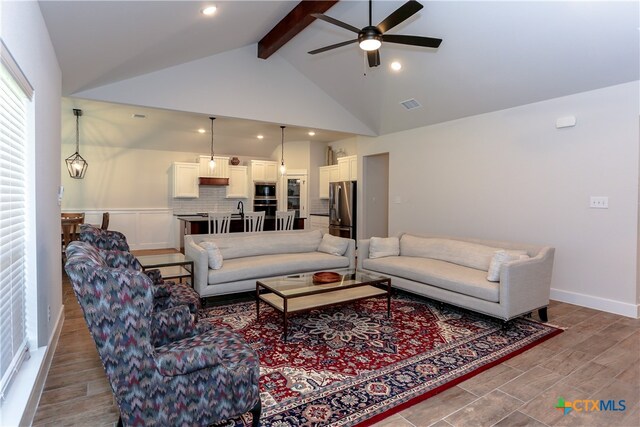 living room with vaulted ceiling with beams, wood-type flooring, and ceiling fan