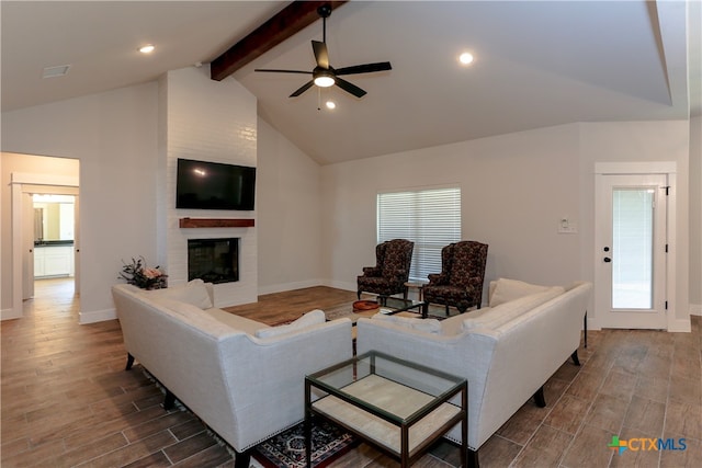 living room featuring a fireplace, wood-type flooring, a healthy amount of sunlight, and beam ceiling