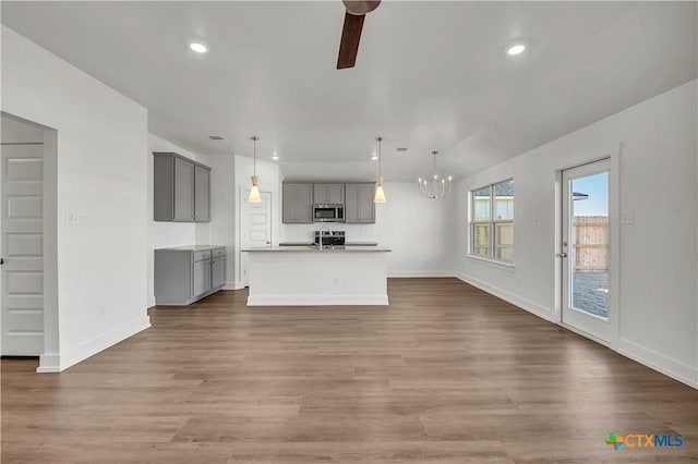 unfurnished living room featuring sink, hardwood / wood-style flooring, and ceiling fan with notable chandelier